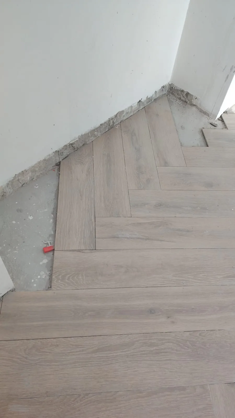 Cut planks and levelling spacers along an unfinished wall