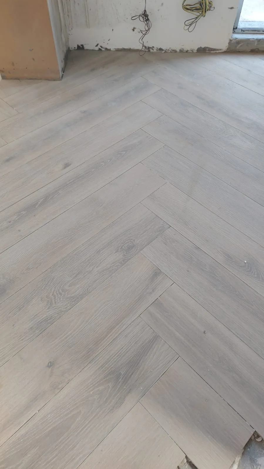 Herringbone flooring meeting an unfinished wall base